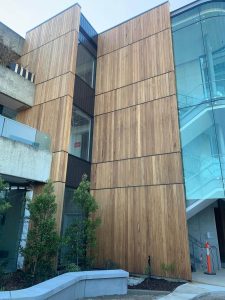 A tall wooden wall supporting a glass building