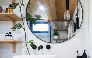 A round mirror isntalled in a tiny home bathroom